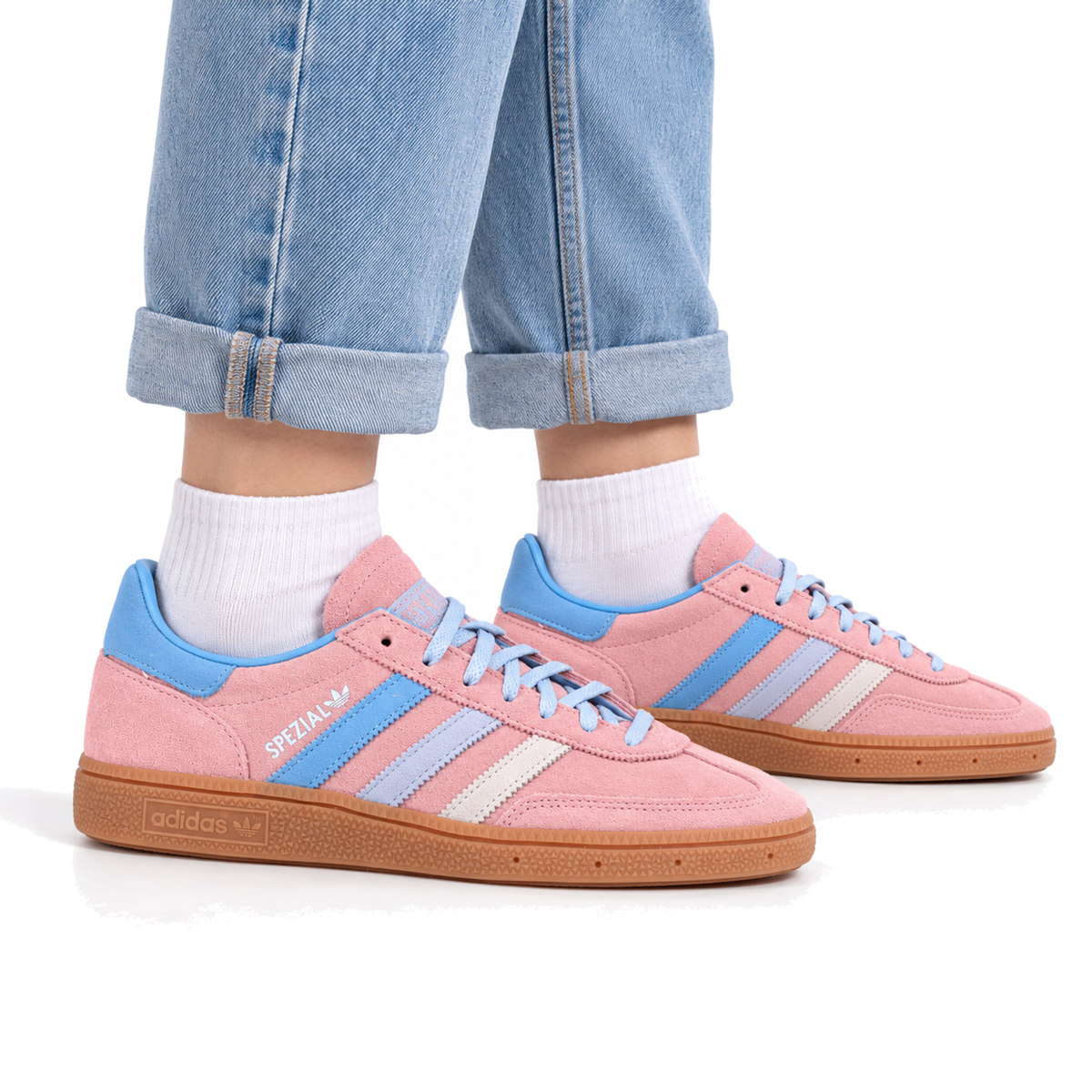 Lifestyle styling image of an adult woman wearing pink and blue Handball Spezial sneakers with cuffed denim and white socks