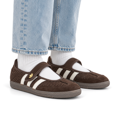 Adult wearing right-facing adidas Originals Samba Jane Brown Off White Gold shoes with light wash jeans and white socks