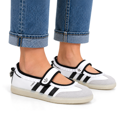 Woman wearing white and black adidas Samba Jane Ruffle shoes with cuffed blue jeans, showing the silver strap details and pale soles.