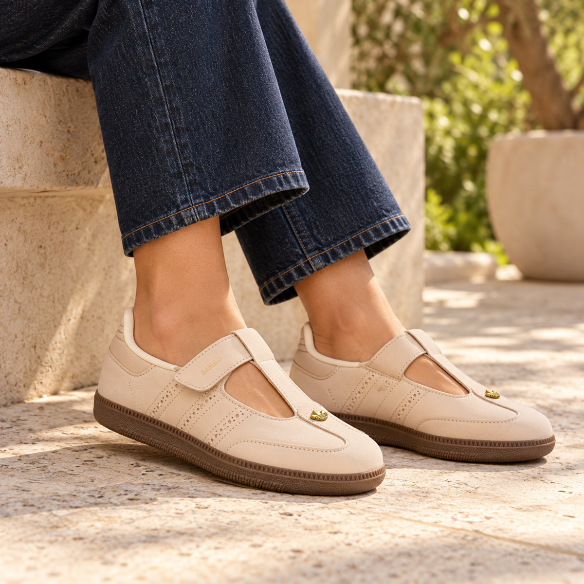 adidas Samba Jane Crystal Sand shoes styled with dark indigo jeans beside a limestone bench
