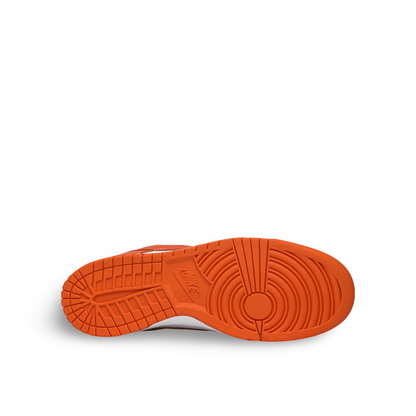 The image shows the sole of an orange Nike sneaker, featuring a circular tread pattern and the Nike logo in the center.